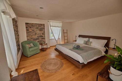 - une chambre avec un grand lit et une chaise verte dans l'établissement Osteria Manciana con Alloggio by Stay Generous, à Scudellate