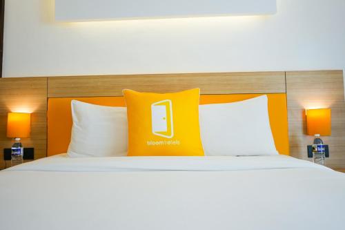 a bed with an orange pillow with a phone on it at BloomSuites l Calangute in Calangute