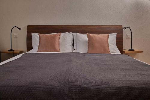 a large bed with pillows and two lamps at Osteria Manciana con Alloggio MONTE GENEROSO in Scudellate