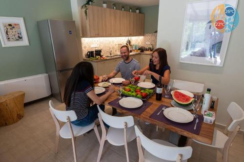 drie mensen zitten rond een tafel in een keuken bij Country Home - Kalamata Villas in Kalamata