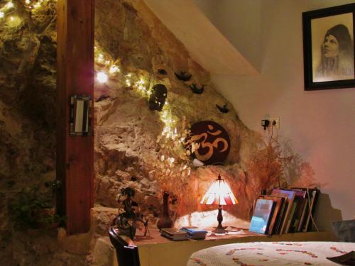 a bedroom with a stone wall with a table with a lamp at Hostal de la Luz in Cuenca