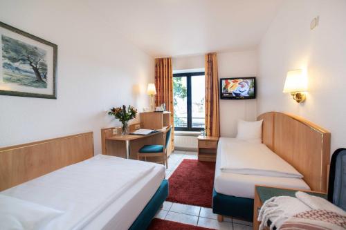 a hotel room with two beds and a desk at UNO Hotel Posthof Saarlouis in Saarlouis