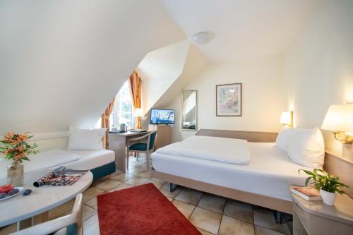 a hotel room with two beds and a desk at UNO Hotel Posthof Saarlouis in Saarlouis