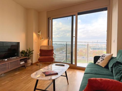 a living room with a green couch and a large window at Apartamento de diseño con Gym y Piscina in Castellón de la Plana