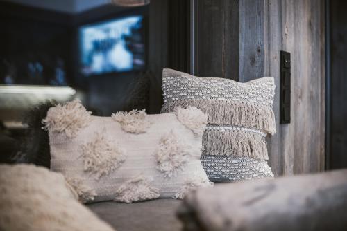 a couch with pillows and a television in a room at Margarethenstein Boutique Hotel in Kaprun