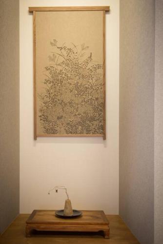 a vase on a wooden table in front of a painting at Jikukan Enishi in Taisha