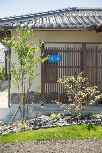 a fence in front of a house with two trees at Jikukan Enishi in Taisha