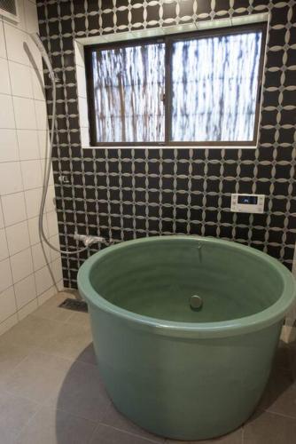 a green bath tub in a bathroom with a window at Jikukan Enishi in Taisha