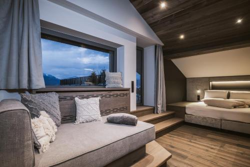 a bedroom with a couch and a large window at Margarethenstein Boutique Hotel in Kaprun