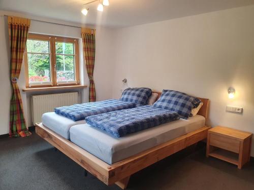 a bedroom with two beds with blue pillows and a window at FeWo Stegenbach Oberstaufen/Steibis in Oberstaufen