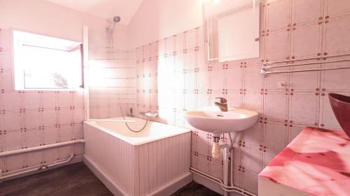 baño con paredes de azulejos rosas y lavabo en Gîte de la Harpe au 4, en Vauvillers