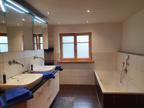 a bathroom with two sinks and a tub and a mirror at FeWo Stegenbach Oberstaufen/Steibis in Oberstaufen