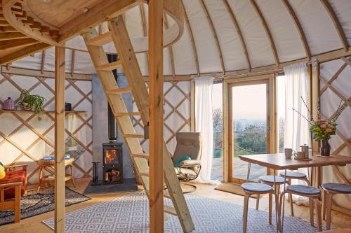 Habitación con escalera de madera en una yurta en Puckaster Cove Luxury Yurt en Niton