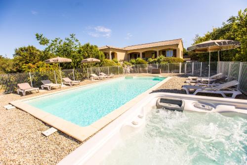 a swimming pool with chairs and a house at Les Villas de Perret in Joyeuse