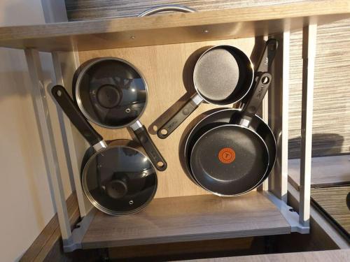 four pots and pans sitting on a shelf at Comfortable ground floor studio apartment. in Carlisle