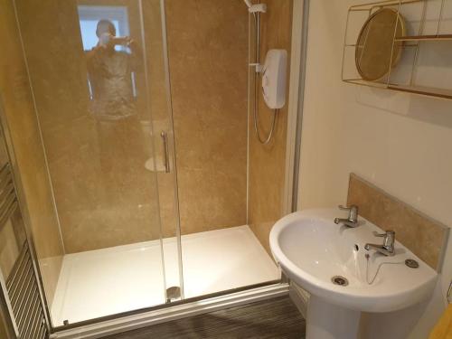 a man taking a picture of a shower in a bathroom at Comfortable ground floor studio apartment. in Carlisle