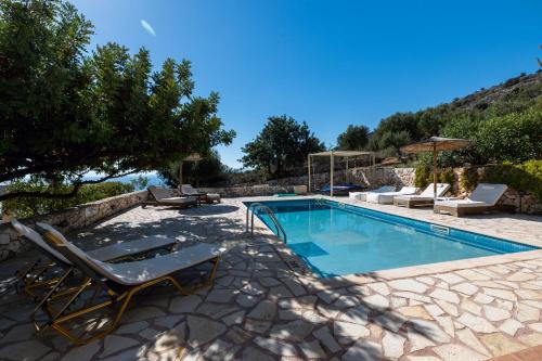 a swimming pool with lounge chairs next to a house at Astra Villas in Skala Kefalonias