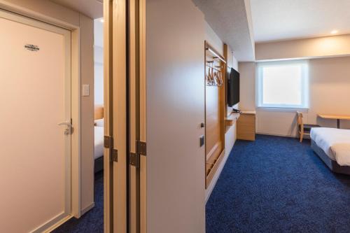 a hotel room with a bed and a bathroom at Sotetsu Grand Fresa Kumamoto in Kumamoto