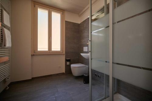 a bathroom with a toilet and a window at Ostello Scudellate MONTE GENEROSO in Scudellate