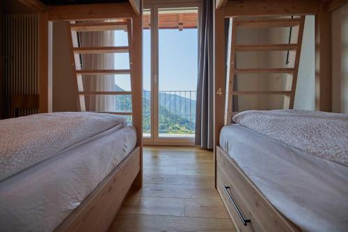 two bunk beds in a room with a large window at Ostello Scudellate MONTE GENEROSO in Scudellate