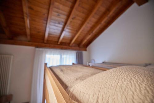 a bedroom with a bed with a wooden ceiling at Ostello Scudellate MONTE GENEROSO in Scudellate
