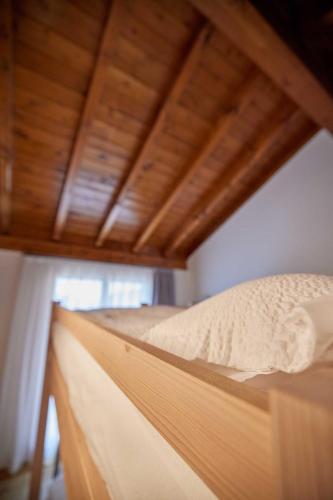 a bed in a room with a wooden ceiling at Ostello Scudellate MONTE GENEROSO in Scudellate
