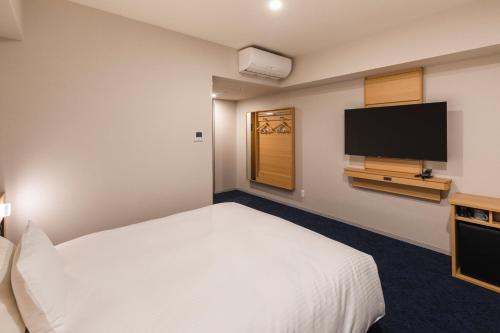 a hotel room with a bed and a flat screen tv at Sotetsu Grand Fresa Kumamoto in Kumamoto