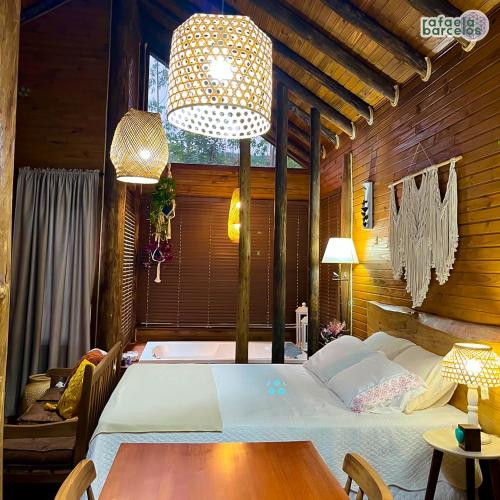 a bedroom with a large bed and a table at Vale das Águas Chalé in Treviso