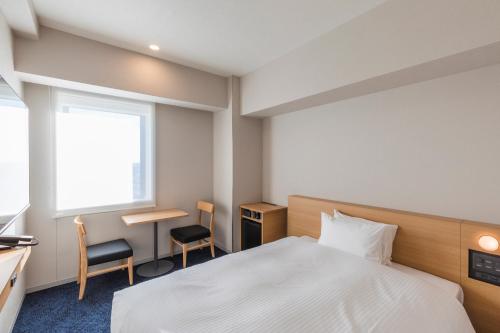 a hotel room with a bed and a desk and a window at Sotetsu Grand Fresa Kumamoto in Kumamoto