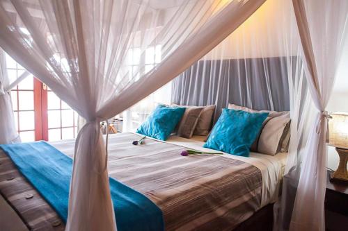 a bedroom with a canopy bed with blue pillows at Luxe GAME-LODGE bordering Kruger in Phalaborwa