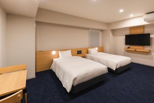 a hotel room with two beds and a flat screen tv at Sotetsu Grand Fresa Kumamoto in Kumamoto