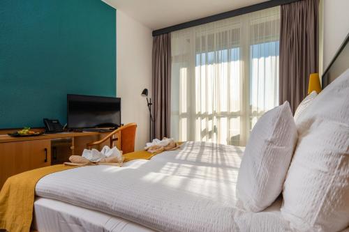 um quarto com uma grande cama branca e uma janela em Zsóry Liget Hotel & Spa Superior em Mezőkövesd