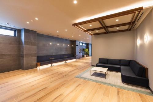 a living room with a black couch and a table at Sotetsu Grand Fresa Kumamoto in Kumamoto