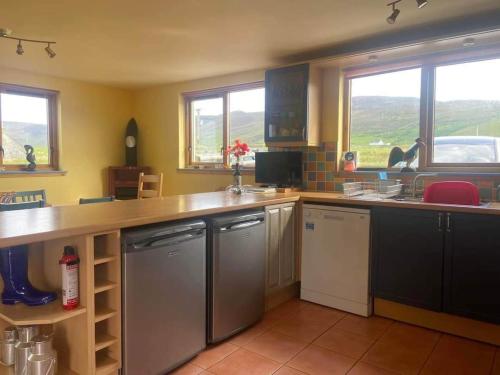 a kitchen with stainless steel appliances and windows at Princes point villa all on ground floor in Portree