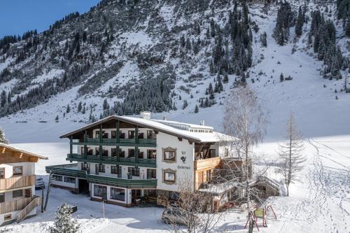 un bâtiment dans la neige devant une montagne dans l'établissement Hubertus, 3 Sterne Superior, à Lech am Arlberg