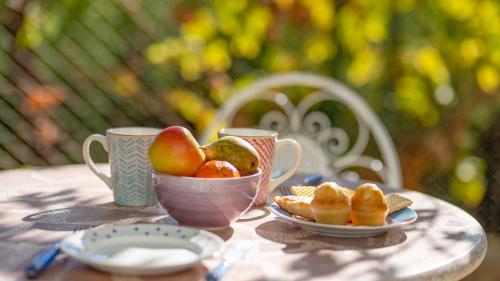 a table with two cups and a bowl of fruit at Casa Ginés Iznájar by Ruralidays in Iznájar