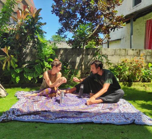 dwoje ludzi siedzących na kocu piknikowym na trawie w obiekcie Hotel Mountain View - Lakeside Pokhara w mieście Pokhara