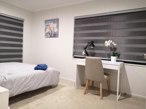 a bedroom with a desk and a bed and a window at Orewa Lovely Cozy Home in Auckland