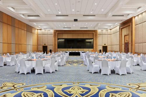 a banquet hall with white tables and chairs and a screen at Pickalbatros The Palace Port Ghalib in Port Ghalib