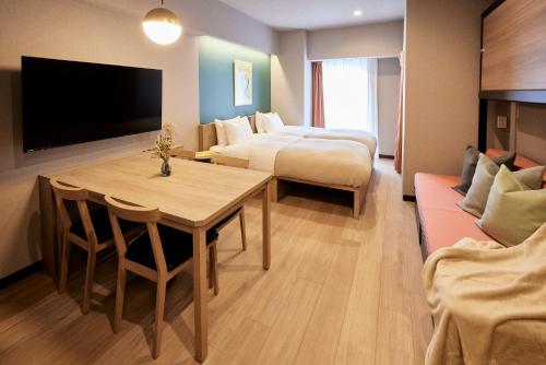 Habitación de hotel con 2 camas, mesa y TV. en Section L Hatchobori en Tokio