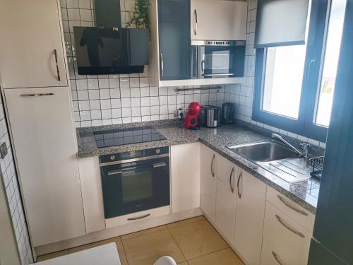 a small kitchen with white cabinets and a sink at CASA CUADERNA a 150 metros de la playa in Playa Honda