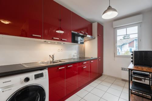 cocina con armarios rojos y lavadora en Atlantic Selection - Proche du golf - Parking Wifi, en Capbreton