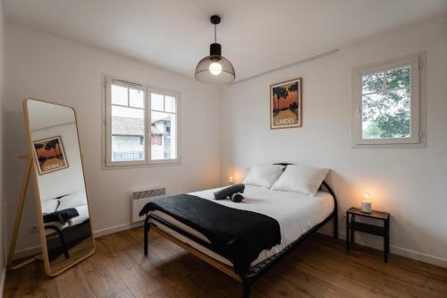 1 dormitorio con 1 cama grande y espejo en Atlantic Selection - Proche du golf - Parking Wifi, en Capbreton