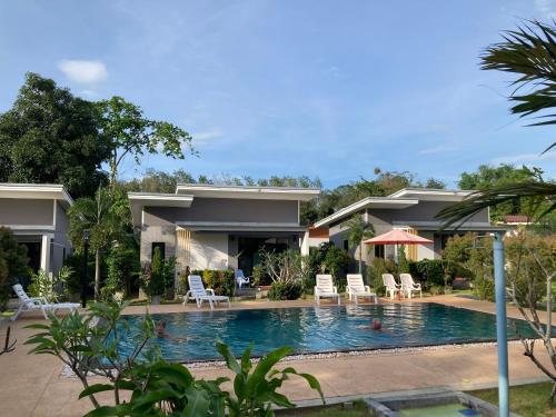 a villa with a swimming pool in front of a house at Oneandaman Resort in Khao Lak