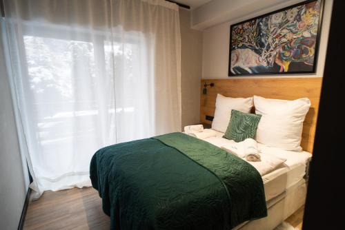 a bedroom with a bed with a green blanket and a window at Apart Invest Centrum Park 3 in Szklarska Poręba