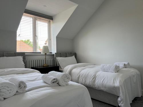 2 camas en una habitación con sábanas blancas y toallas en Pass the Keys Newly built house 4 mins from Twyford Centre en Reading