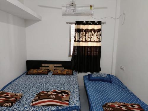 een kamer met 2 bedden en een raam met gordijnen bij Ekta Homestay in Garudeshwar