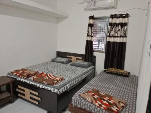 een kamer met 2 bedden en een raam bij Ekta Homestay in Garudeshwar
