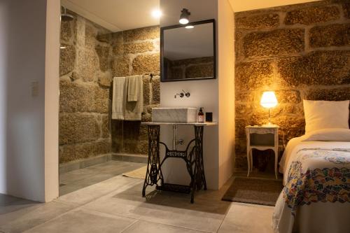 a bathroom with a bed and a sink and a mirror at Casa da Portela - Sem Igual in Meinedo
