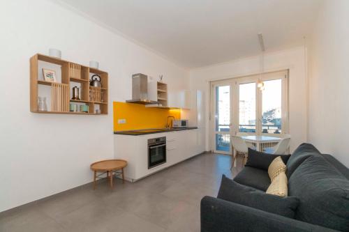 a living room with a blue couch and a kitchen at Urban House Carducci - Apartments in Turin